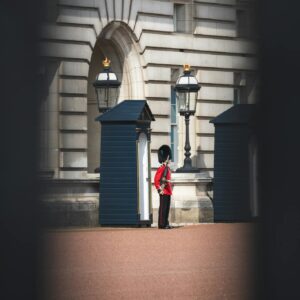 Person in Red Jacket and Black Pants Standing on Brown Brick Floor